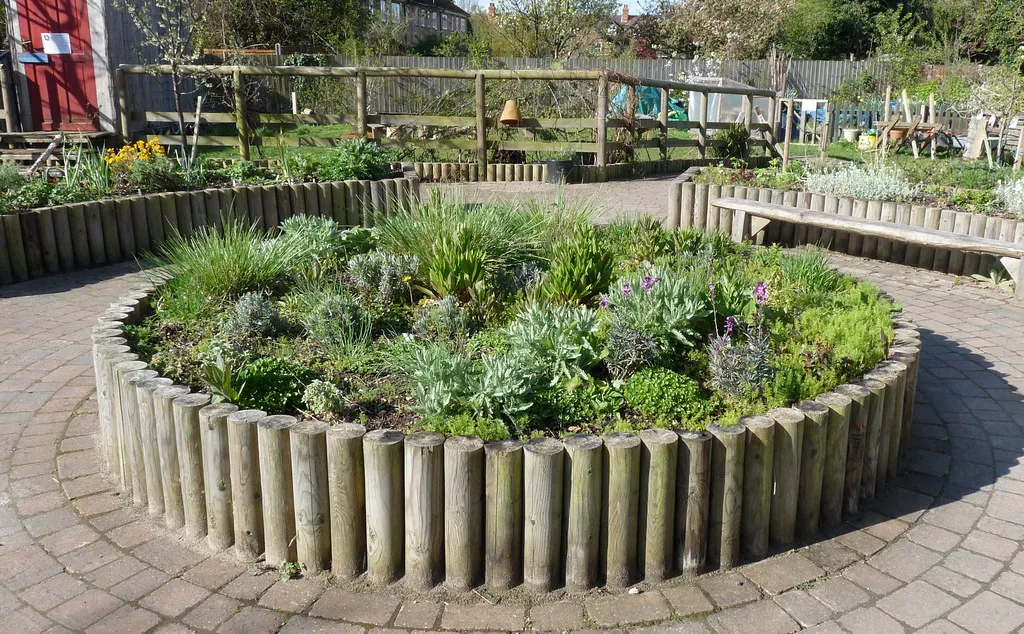 Massif rond de plantes aromatiques bordé de rondins