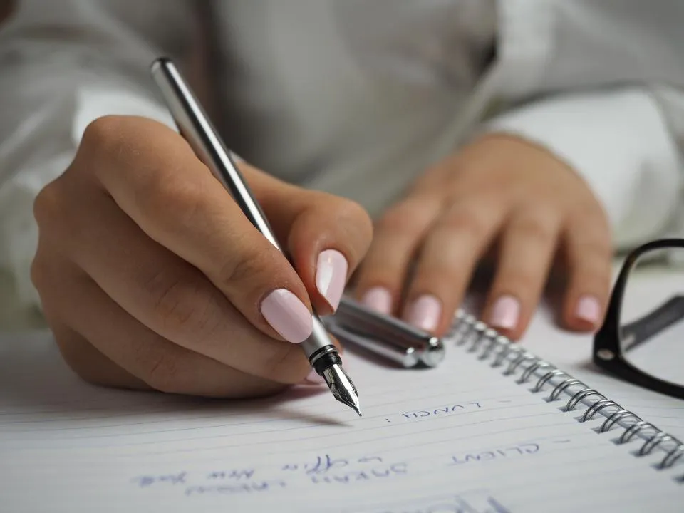 Main qui prend des notes au stylo plume sur un carnet
