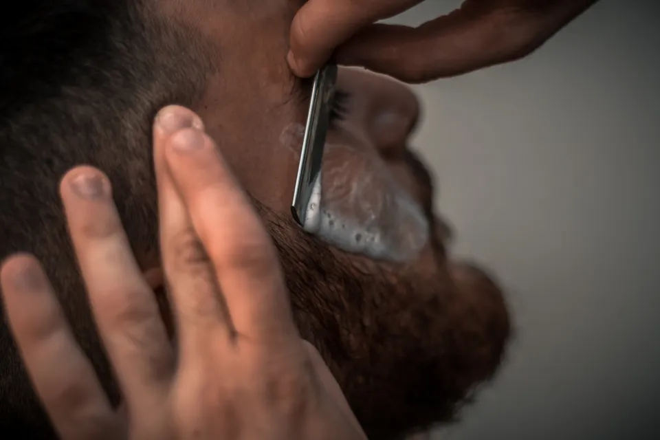 Rasage d'une barbe au coupe-chou, en gros plan