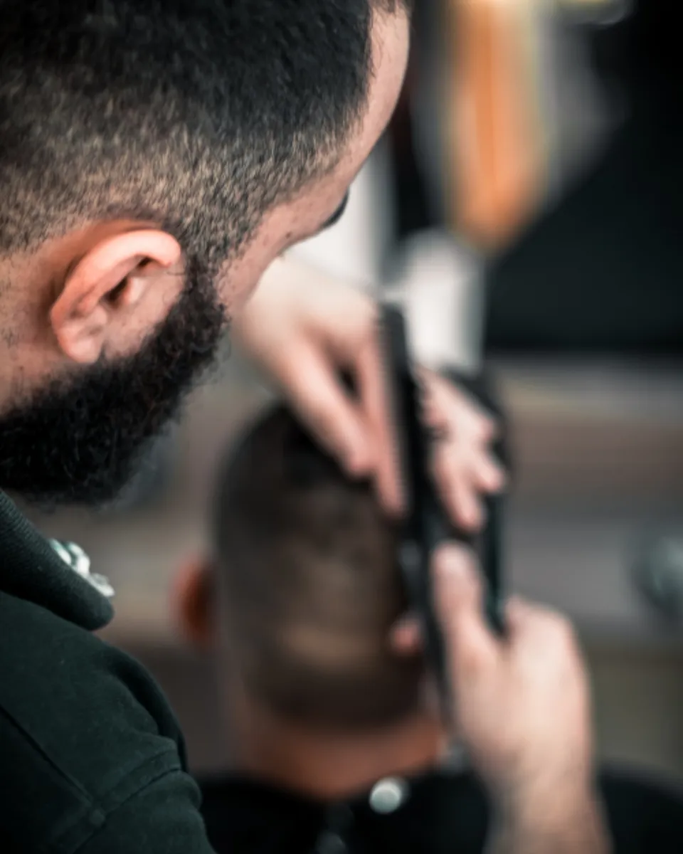 Barbier réalisant une coupe à la tondeuse