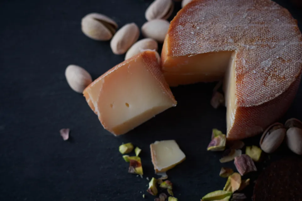 Fromages affinés et pistaches sur une ardoise sombre