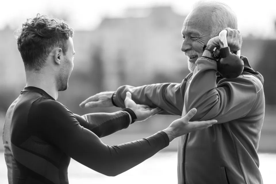 Coach accompagnant un homme âgé dans un exercice d'étirement