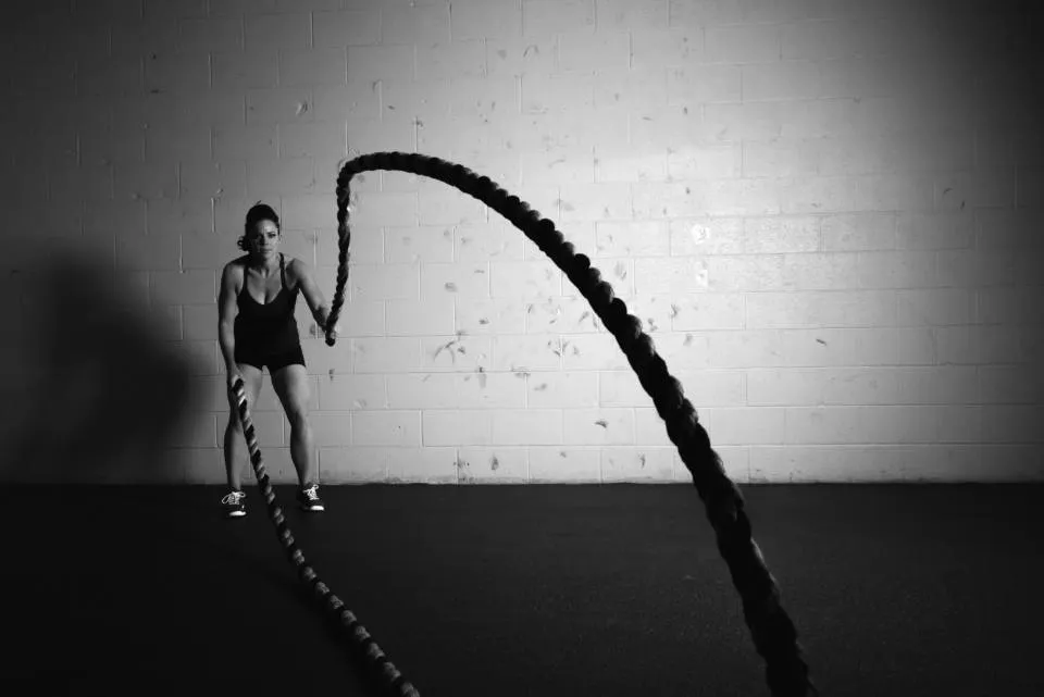 Sportive travaillant avec des cordes ondulatoires dans une salle sombre