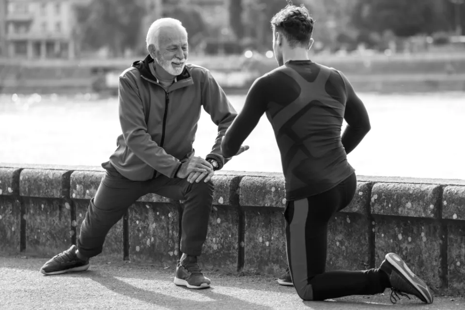Coach guidant un étirement des jambes en extérieur