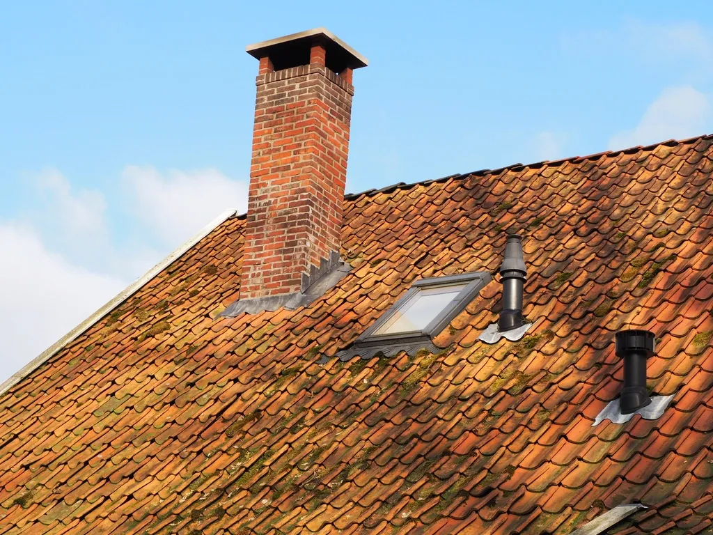 Toiture en tuiles avec cheminée en briques et fenêtre de toit