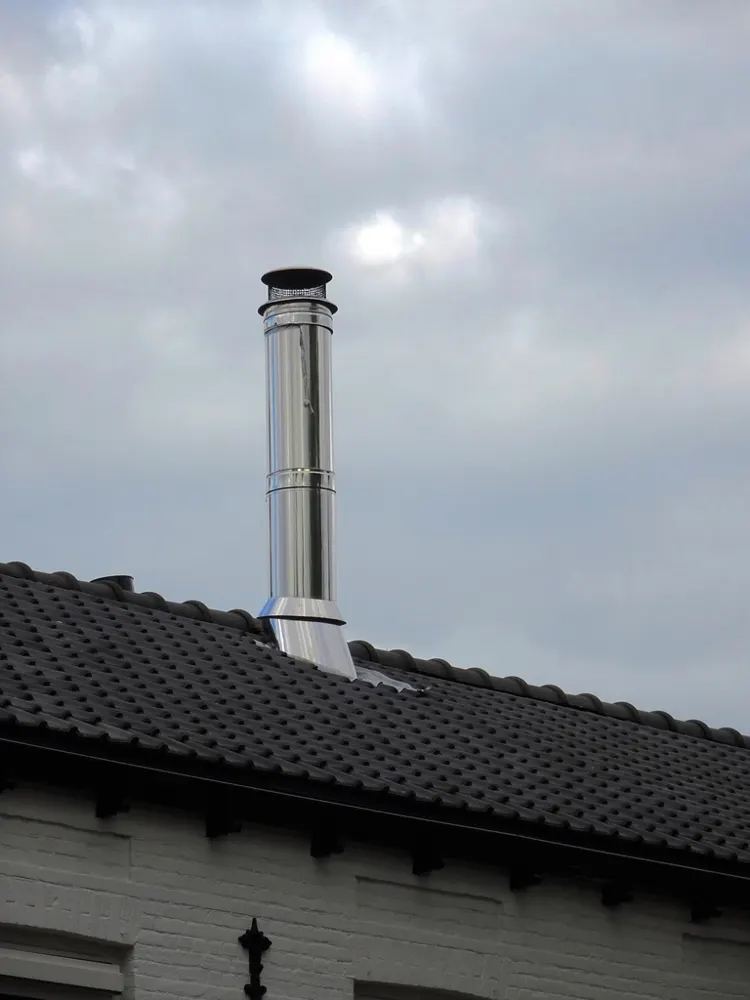 Conduit de cheminée en inox sur une toiture en tuiles noires