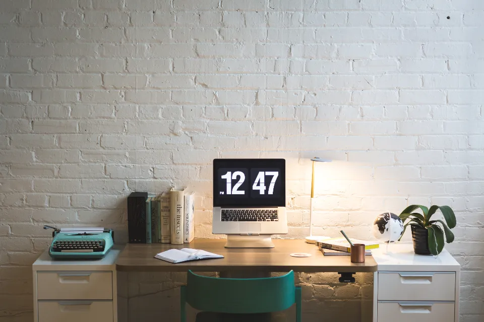Bureau lumineux avec mur de briques blanches, ordinateur et plantes