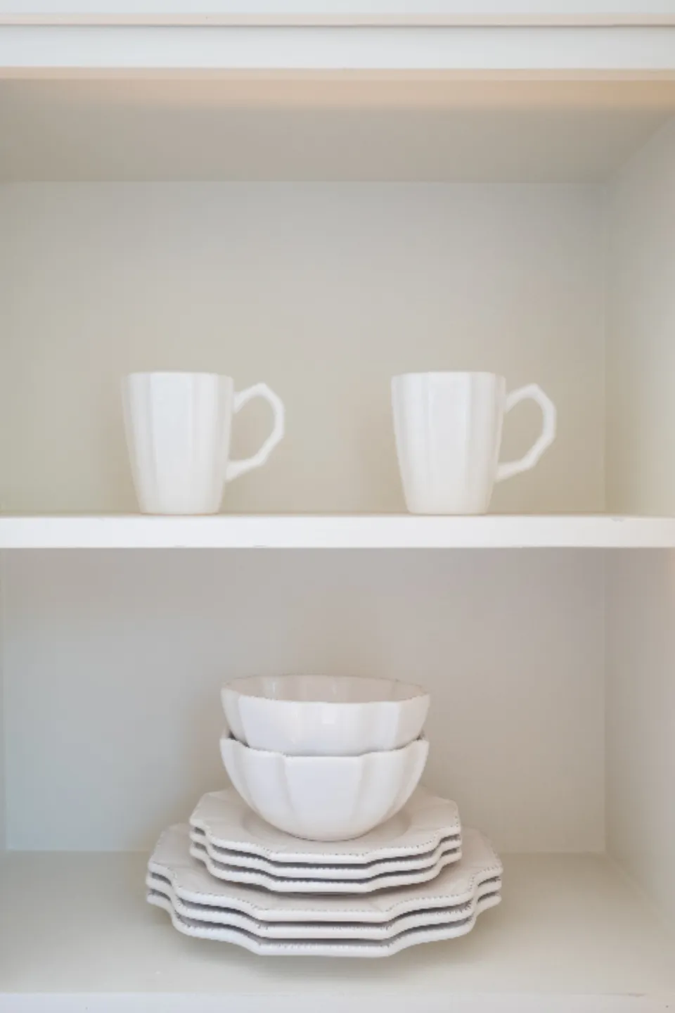 Placard blanc impeccable avec tasses et assiettes rangées