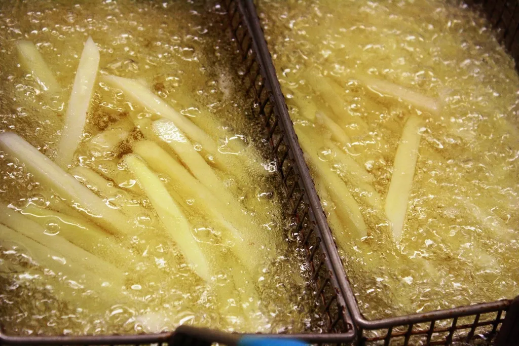 Frites en train de cuire dans les paniers de la friteuse