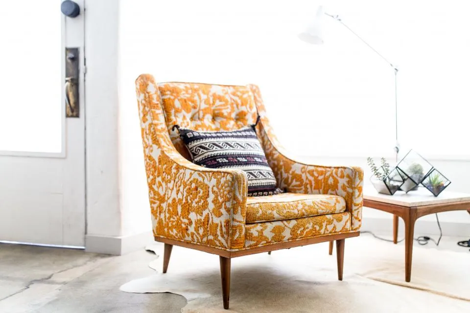 Pièce lumineuse aux murs blancs avec fauteuil fleuri orange