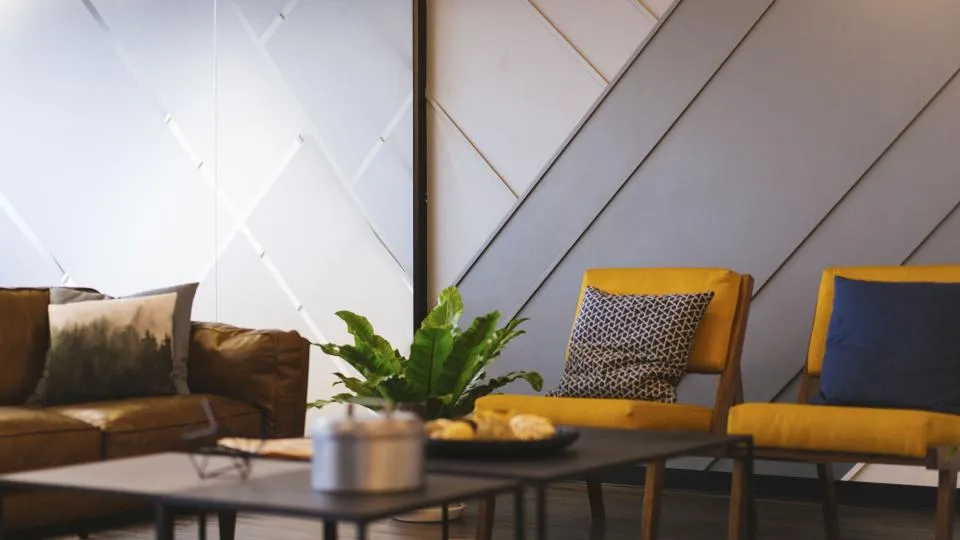 Séjour avec mur décoratif à motifs géométriques et fauteuils jaunes