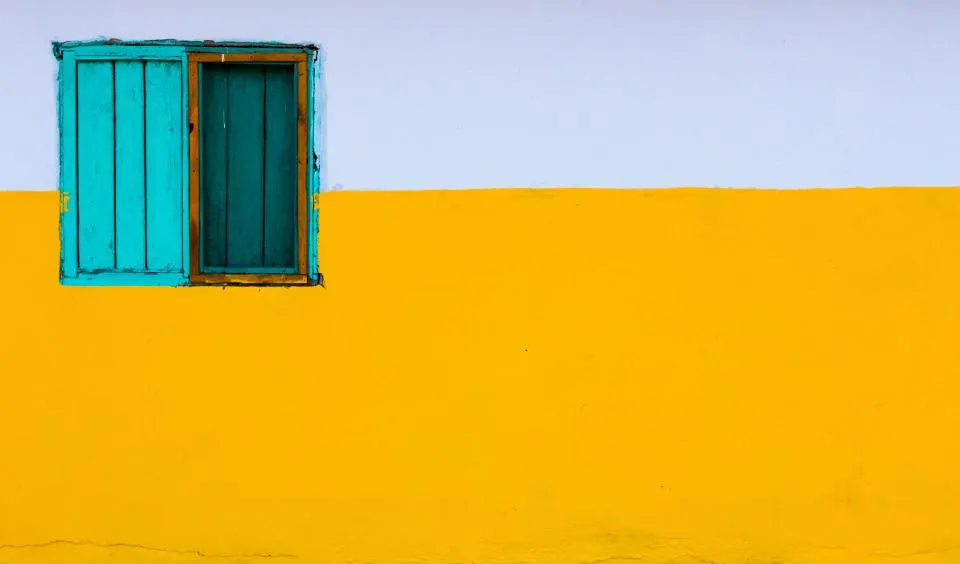 Mur extérieur jaune safran avec volets turquoise