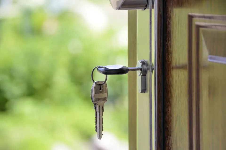 Clé insérée dans la serrure d'une porte d'entrée ouverte sur un jardin