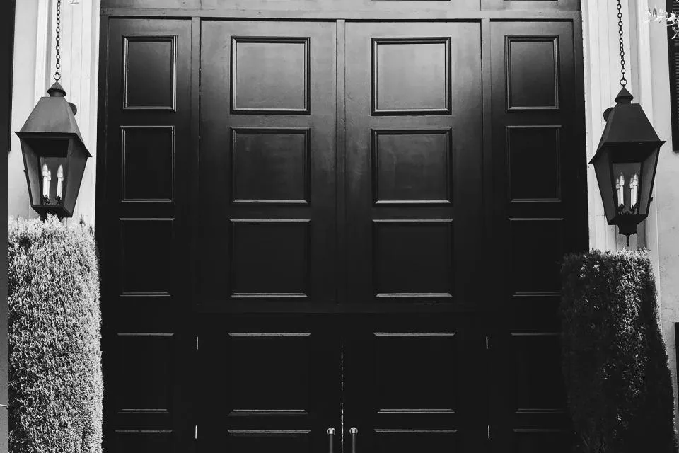 Grande porte d'entrée noire encadrée de deux lanternes