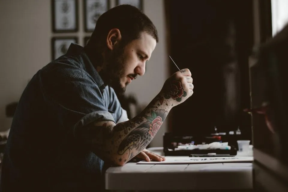Tatoueur concentré sur un dessin à sa table