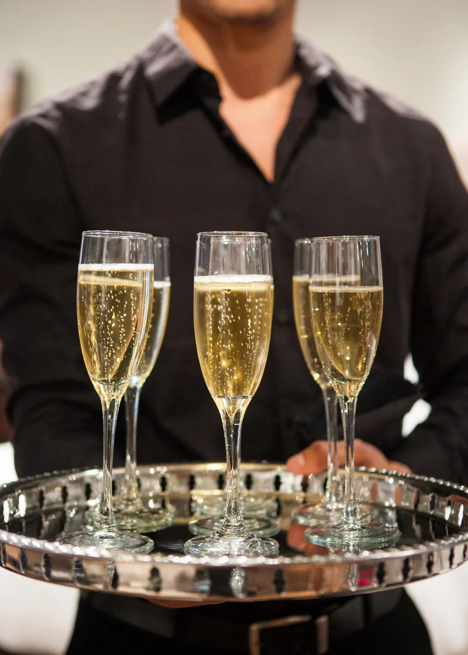 Maître d'hôtel portant un plateau de coupes de champagne