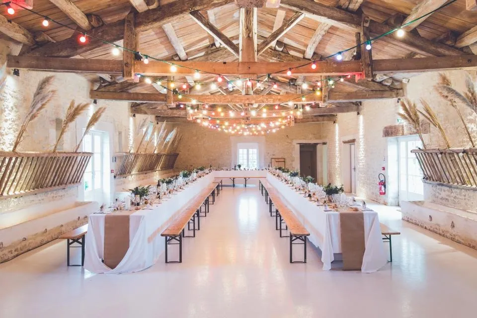 Grande salle de réception aux poutres apparentes avec longues tables
